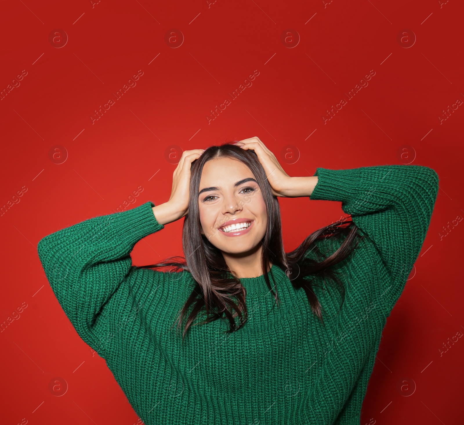 Image of Pretty woman wearing warm sweater on red background 