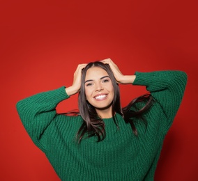 Pretty woman wearing warm sweater on red background 