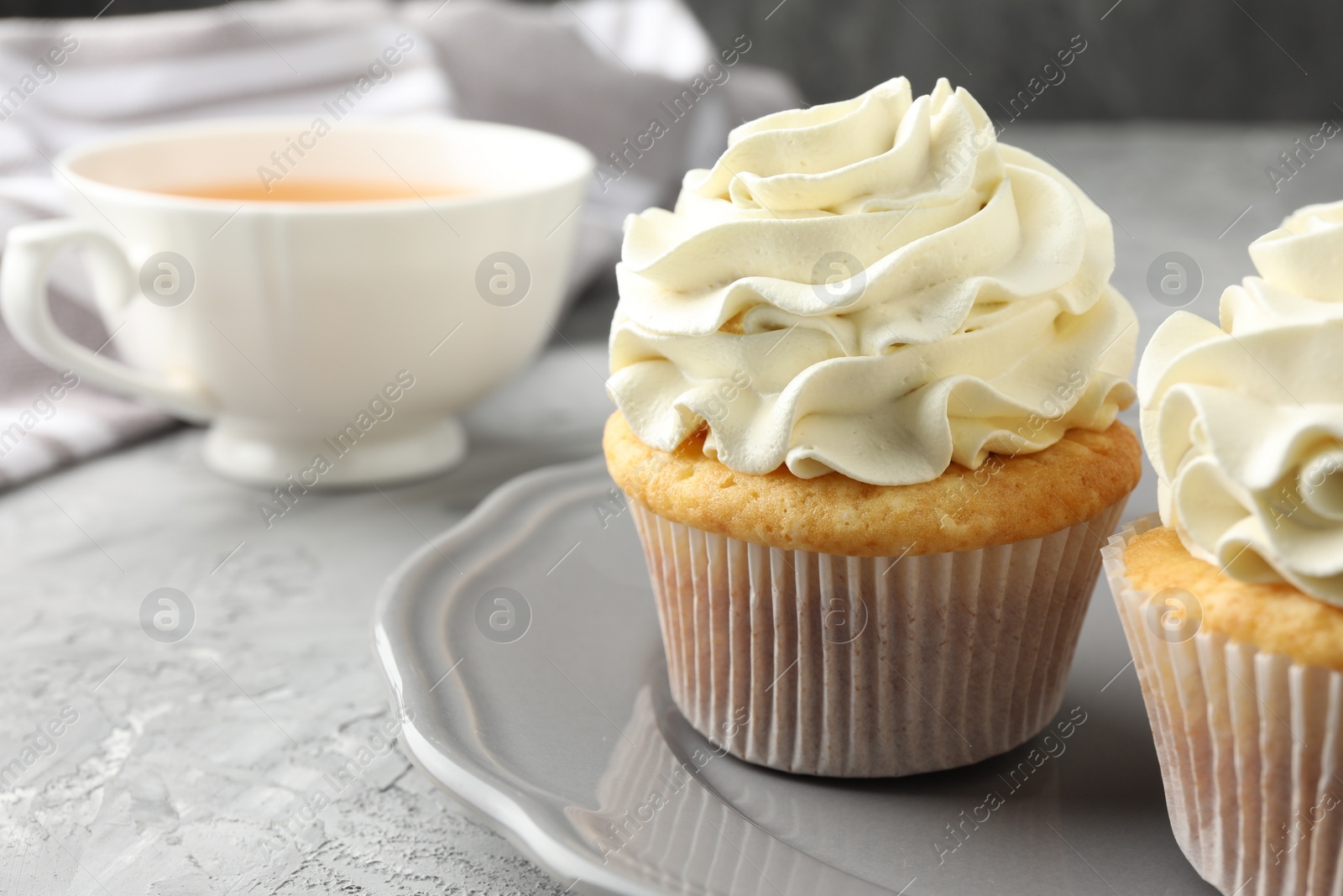 Photo of Tasty cupcakes with vanilla cream on grey table, closeup. Space for text