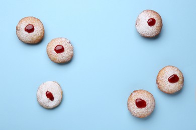 Photo of Hanukkah donuts with jelly and powdered sugar on light blue background, flat lay. Space for text