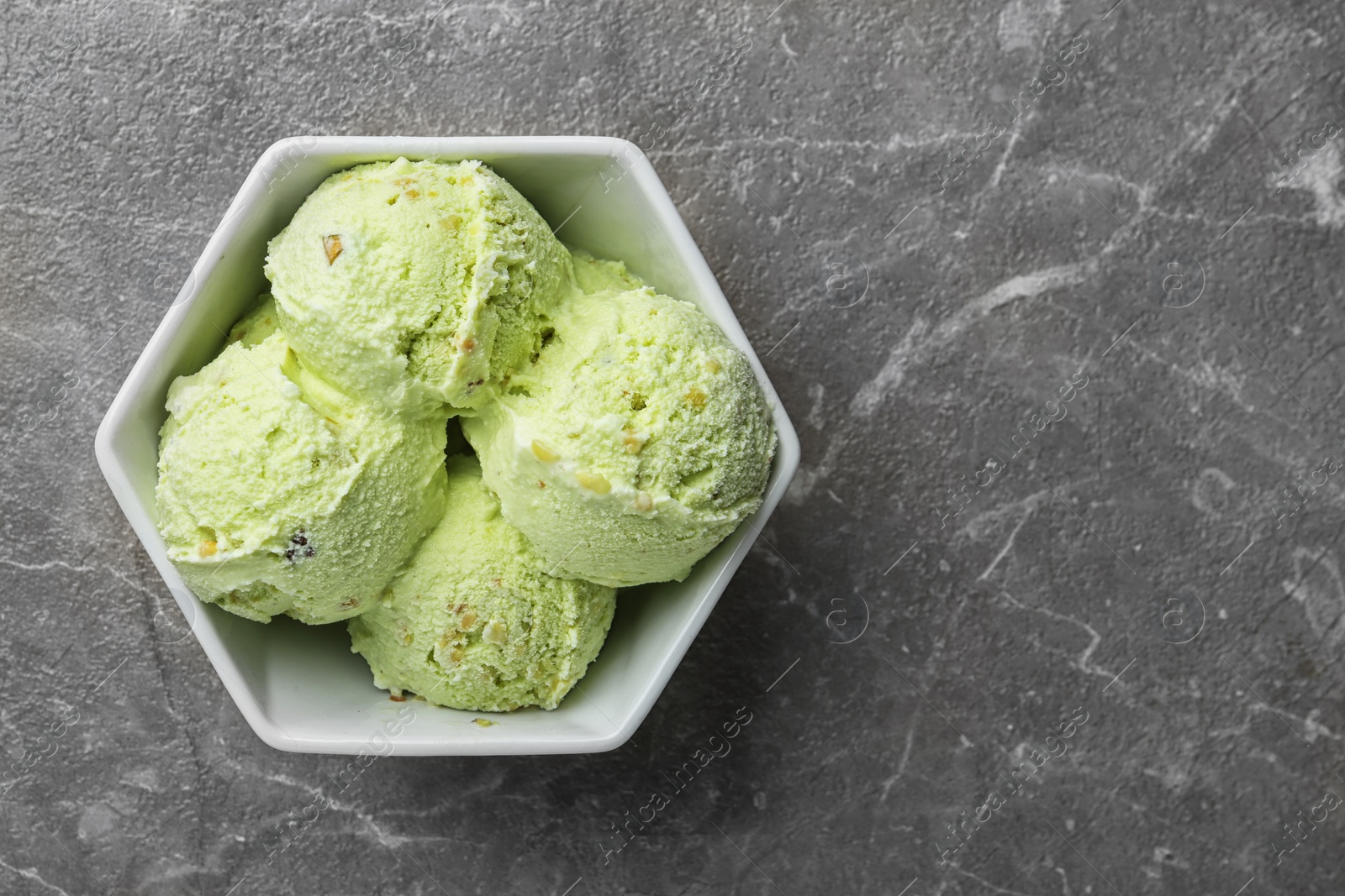 Photo of Delicious pistachio ice cream on grey marble table, top view. Space for text