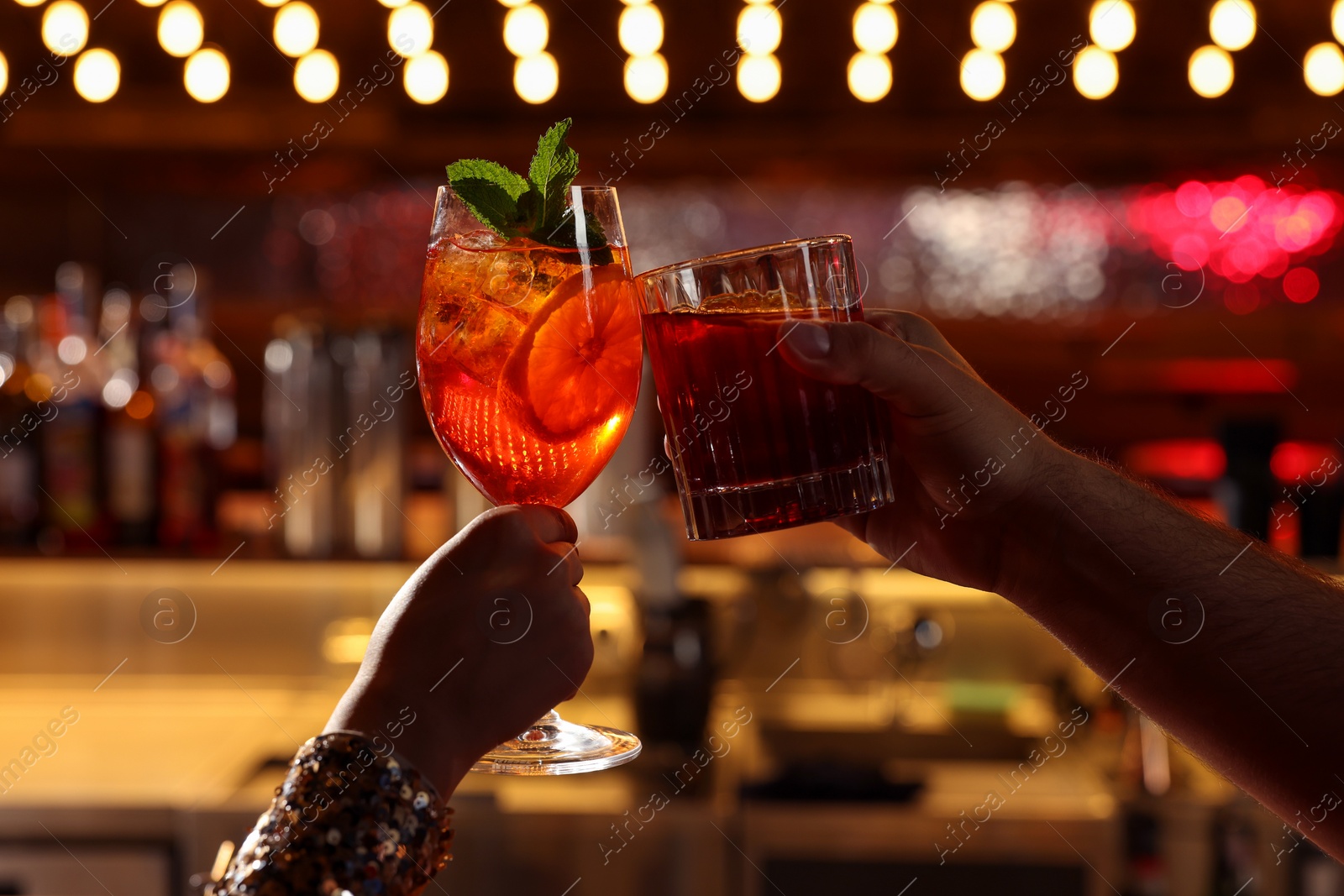 Photo of People clinking glasses with fresh cocktails in bar, closeup