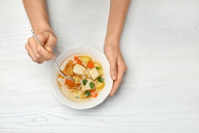 Photo of Woman eating fresh homemade chicken soup at table, top view. Space for text