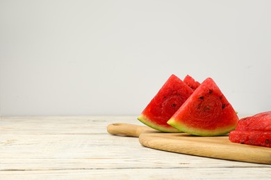 Photo of Slices of delicious ripe watermelon on white wooden table against light background, space for text