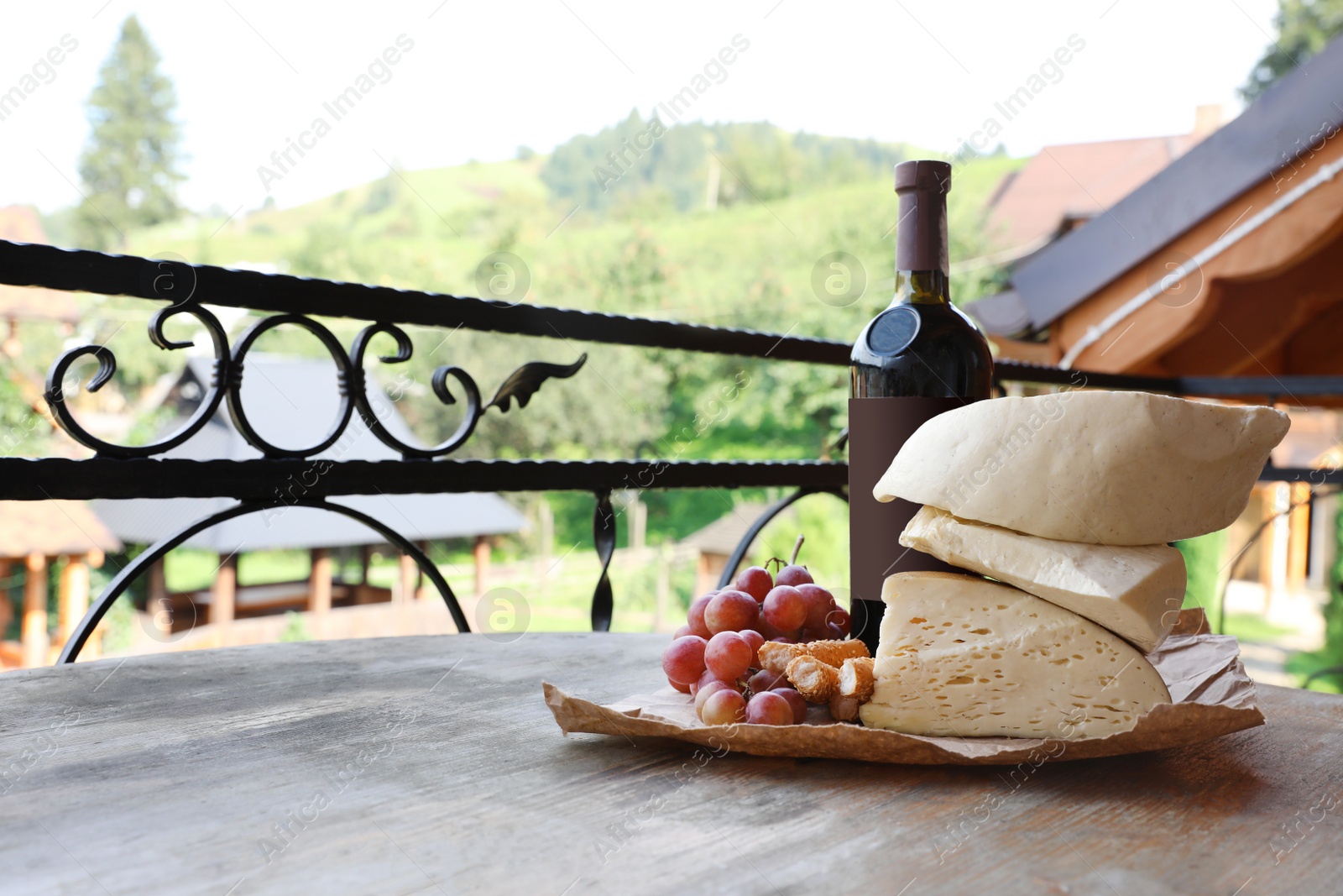 Photo of Bunch of grapes, wine, cheese and peaches on wooden table. Space for text