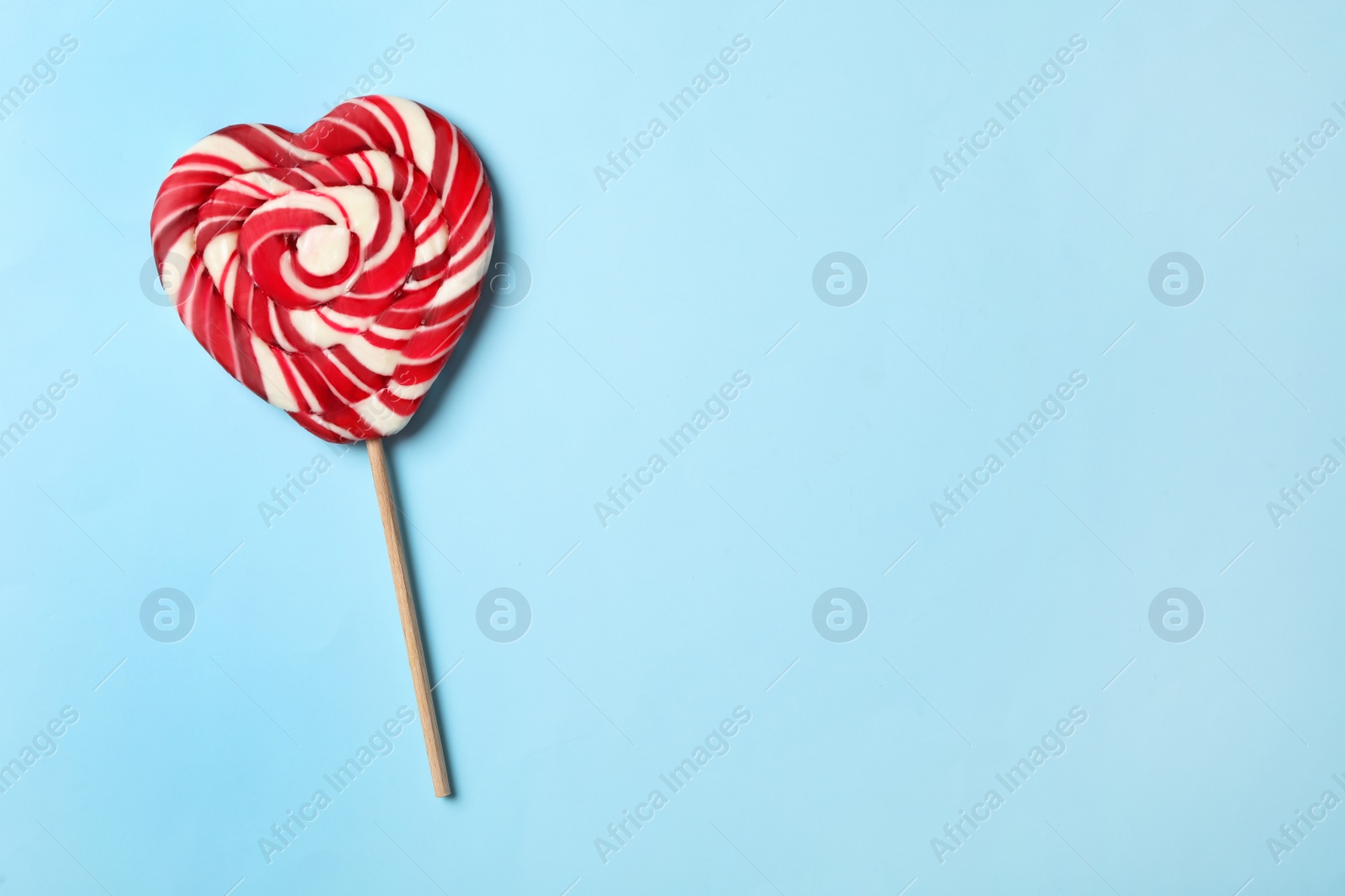 Photo of Sweet heart shaped lollipop on light blue background, top view with space for text. Valentine's day celebration
