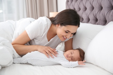 Photo of Happy woman with her sleeping baby on bed