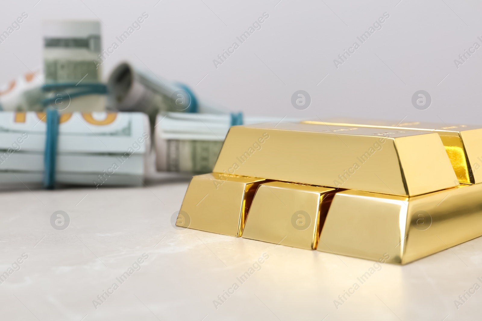 Photo of Shiny gold bars and dollar rolls on table. Space for text