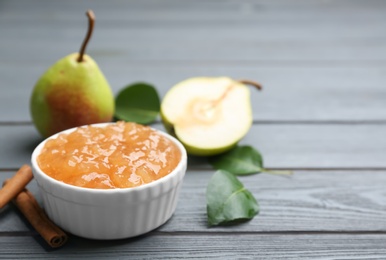 Photo of Delicious pear jam and fresh fruits on grey wooden table. Space for text