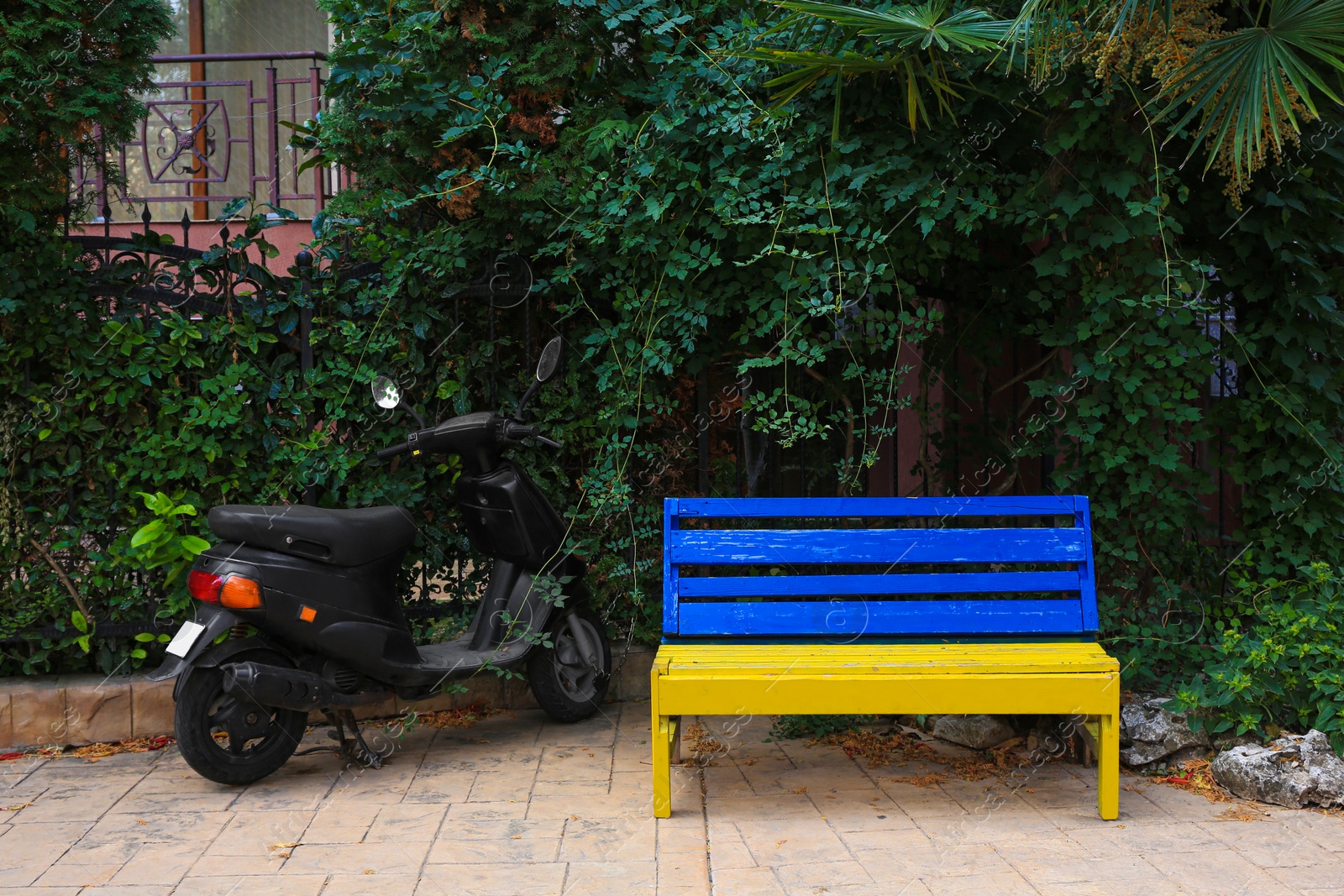 Photo of Beautiful blue and yellow wooden bench near scooter outdoors