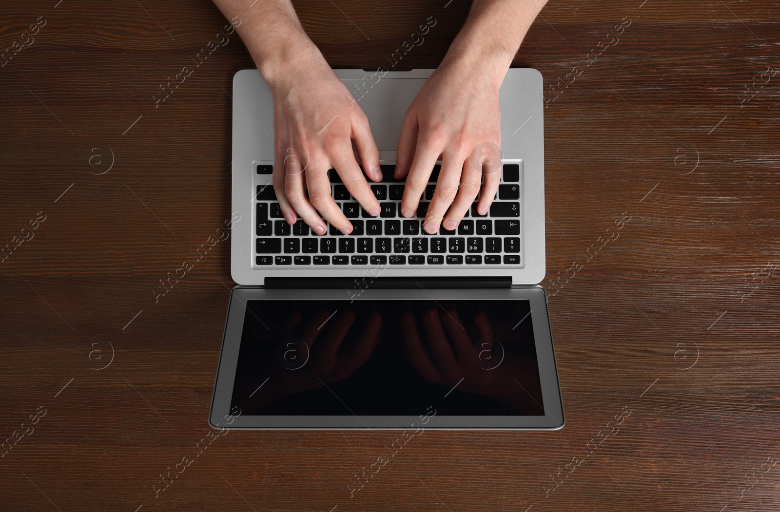 Photo of Man working with laptop at wooden table, top view