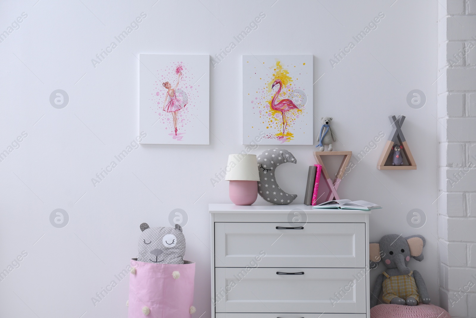 Photo of Chest of drawers and beautiful pictures in children's room. Interior design