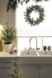 Photo of Small Christmas trees and festive decor in kitchen