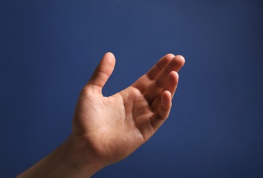 Man holding something in hand on blue background, closeup