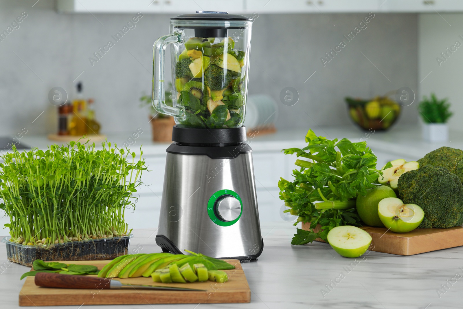 Photo of Blender with ingredients for smoothie and products on white marble table in kitchen