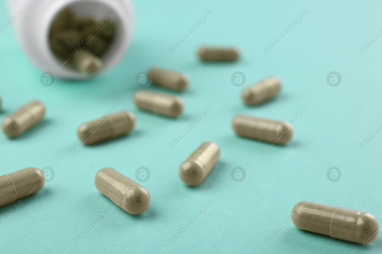 Photo of Bottle and vitamin capsules on turquoise background, closeup