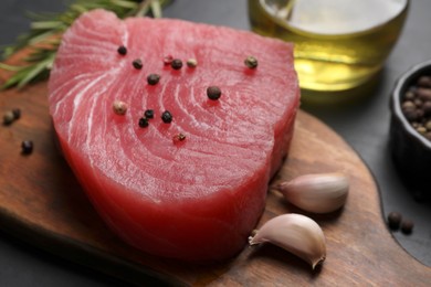 Raw tuna fillet and spices on wooden board, closeup