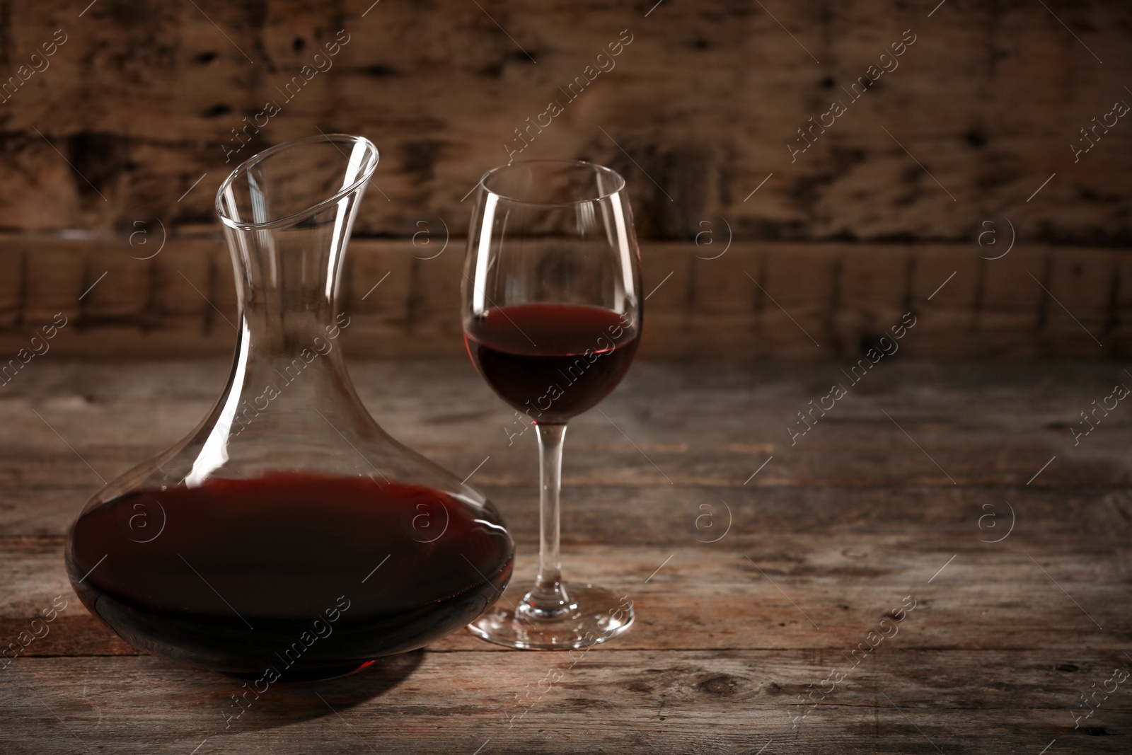 Photo of Elegant decanter and glass with red wine on wooden table