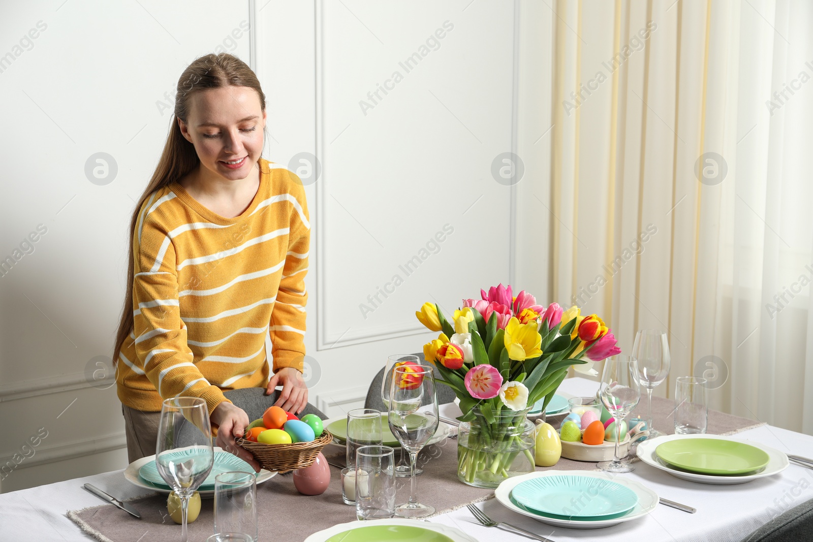 Photo of Woman setting table for festive Easter dinner at home