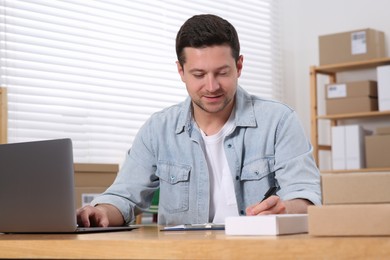 Photo of Seller with parcels and laptop working in office. Online store