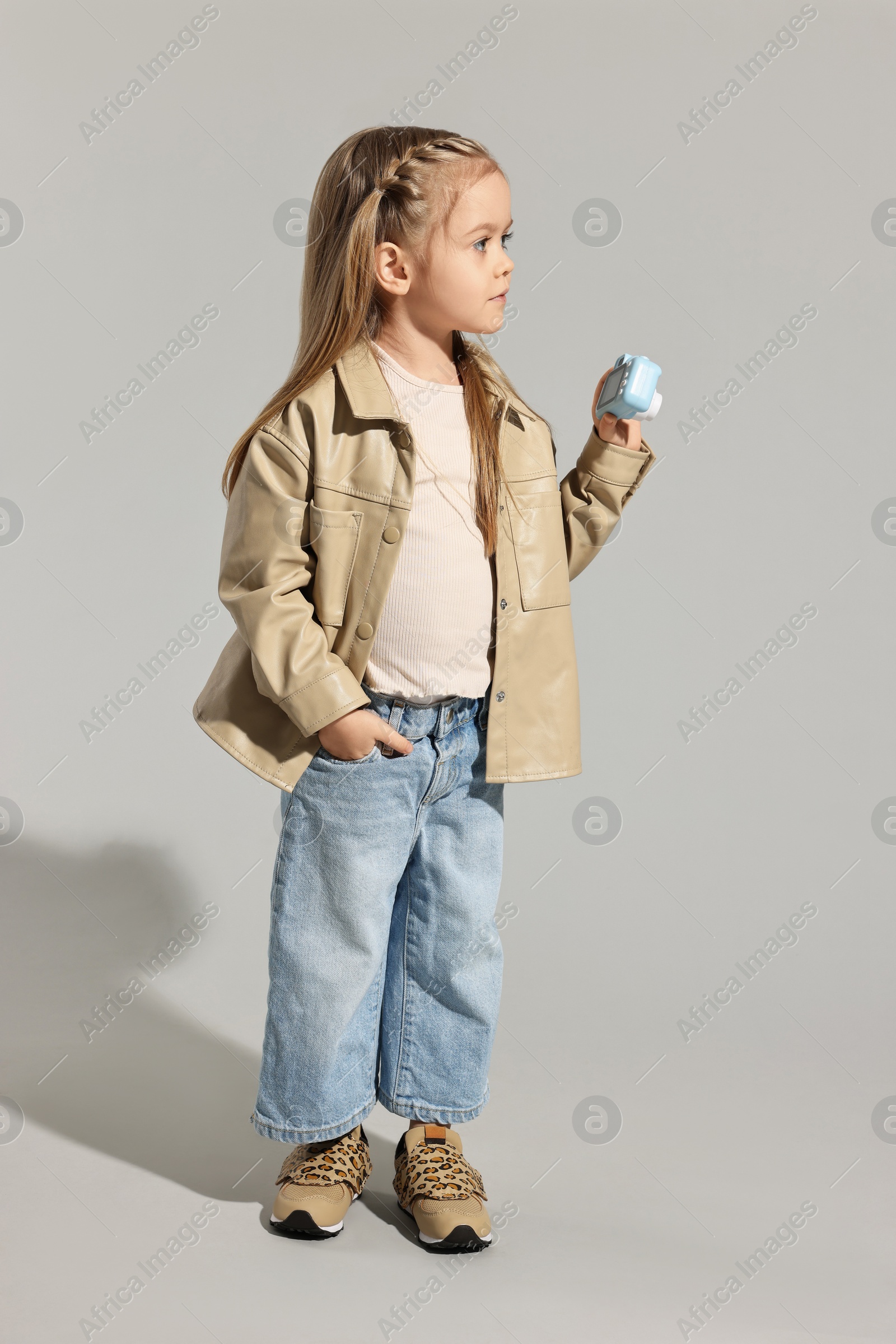 Photo of Fashion concept. Stylish girl with toy camera on light grey background