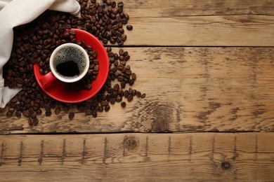 Photo of Cup of aromatic hot coffee and beans on wooden table, flat lay. Space for text