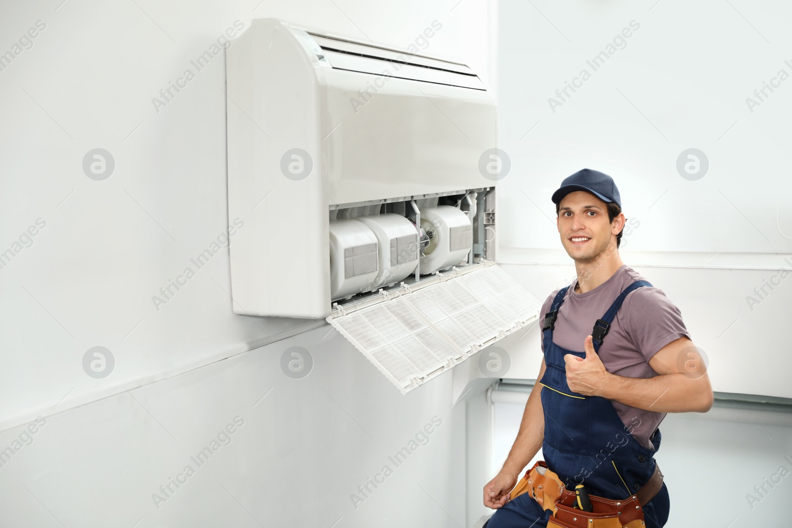 Photo of Male technician standing near air conditioner indoors