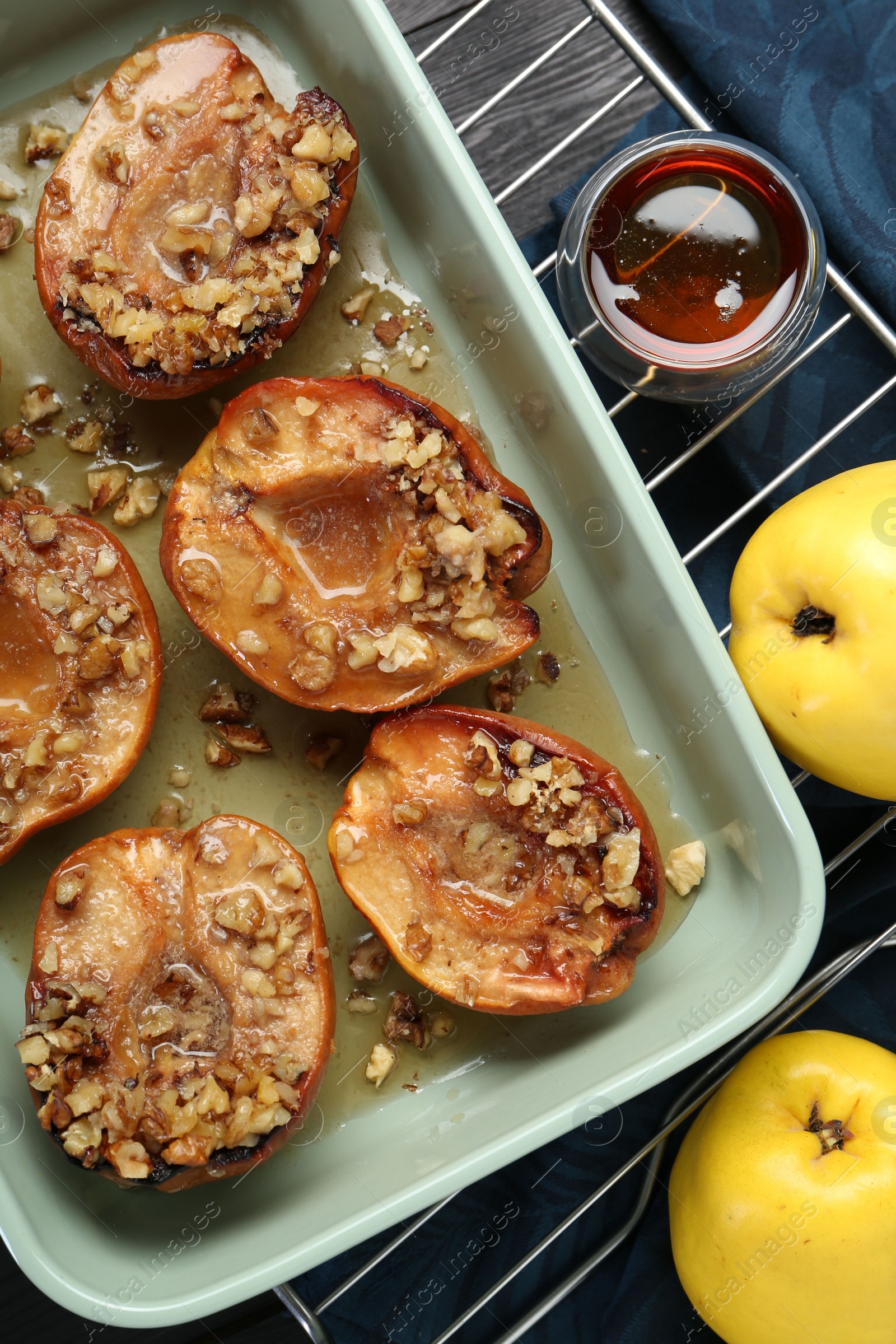 Photo of Tasty baked quinces with nuts and honey in dish on table, flat lay