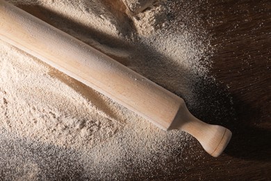 Photo of Pile of flour and rolling pin on wooden table, top view