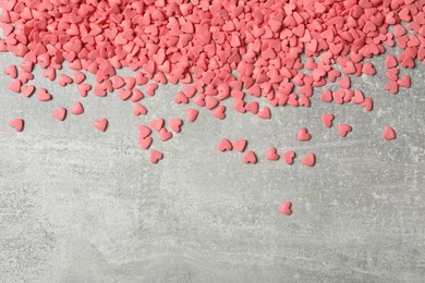 Photo of Pink heart shaped sprinkles on grey table, flat lay. Space for text