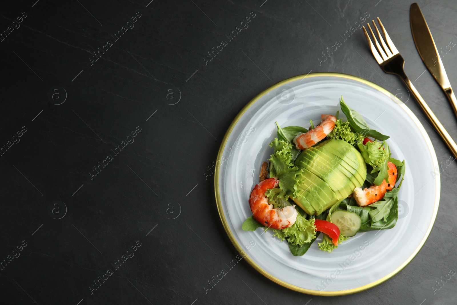 Photo of Delicious avocado salad with shrimps on black table, flat lay. Space for text