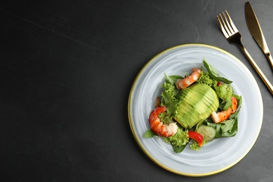 Delicious avocado salad with shrimps on black table, flat lay. Space for text