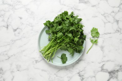 Photo of Bunch of fresh aromatic cilantro on white marble table, flat lay