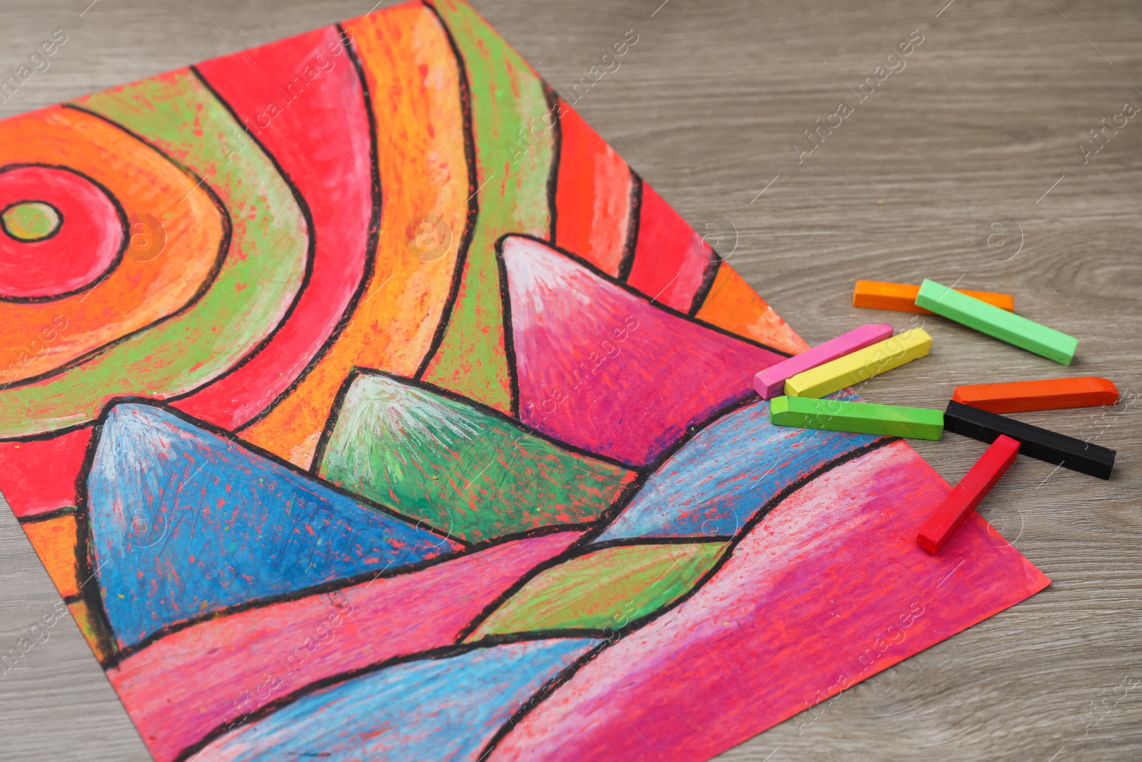 Photo of Beautiful drawing and pastels on wooden table, closeup view