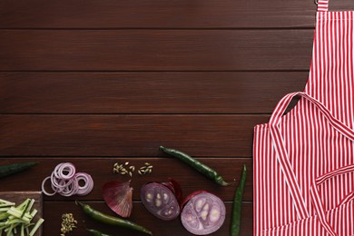 Photo of Flat lay composition with striped apron and different ingredients on wooden table. Space for text