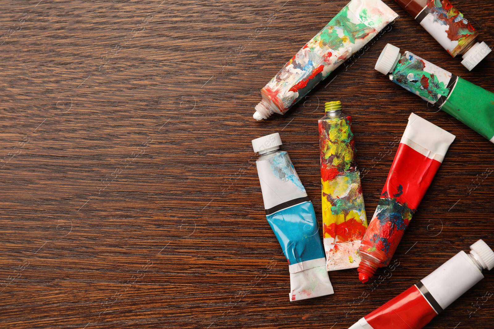 Photo of Tubes with oil paints on wooden table, flat lay. Space for text