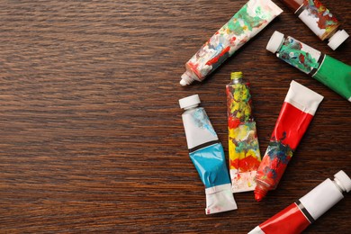 Tubes with oil paints on wooden table, flat lay. Space for text