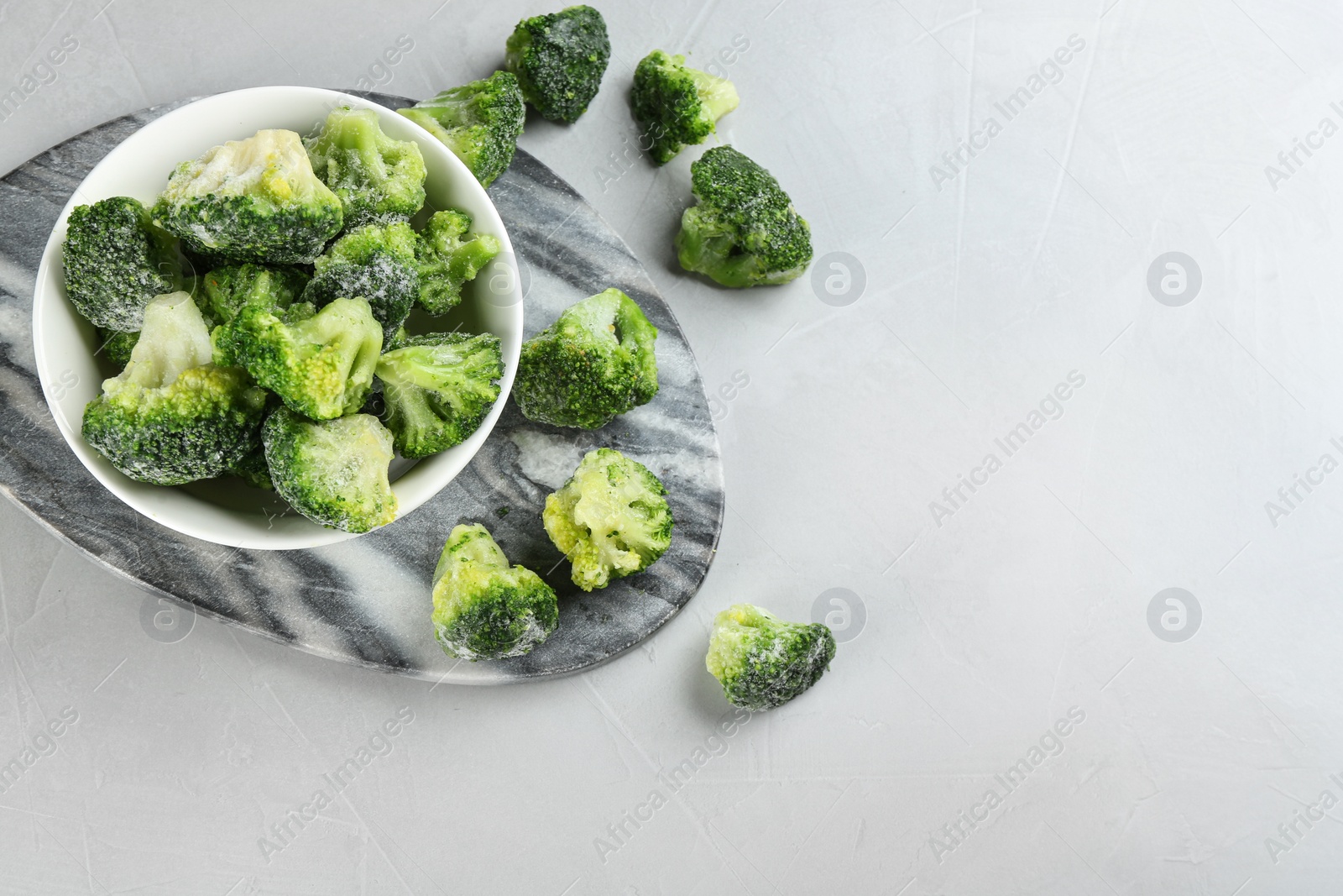 Photo of Frozen broccoli florets on light grey table, flat lay. Vegetable preservation