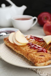 Photo of Fresh tasty puff pastry with jam and apples on white textured table, closeup