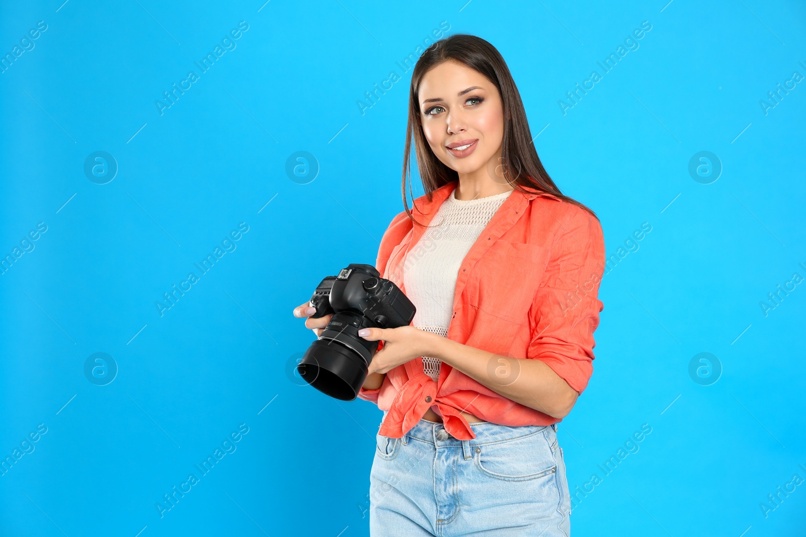 Photo of Professional photographer working on light blue background in studio. Space for text