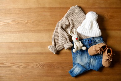 Photo of Children's shoes, clothes, toy and pacifier on wooden table, flat lay. Space for text