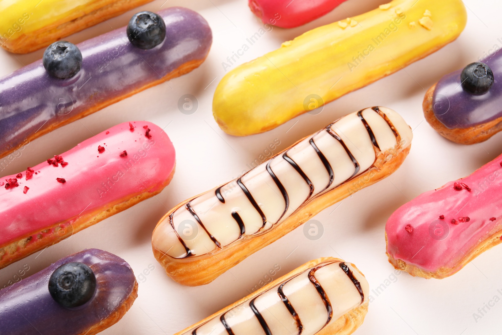 Photo of Delicious eclairs covered with glaze on white background, top view