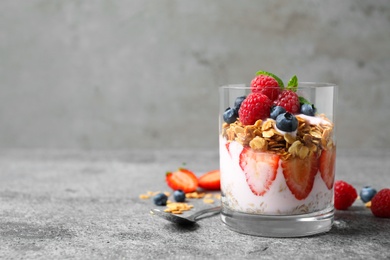 Photo of Glass of tasty homemade granola dessert on grey table, space for text. Healthy breakfast