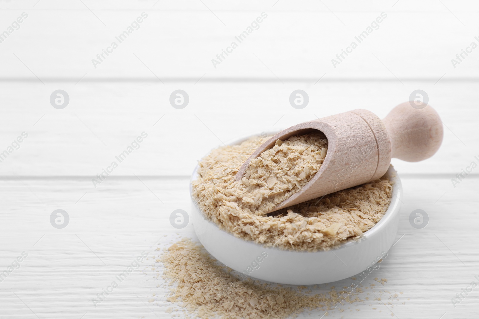 Photo of Beer yeast flakes on white wooden table, closeup. Space for text