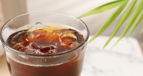 Photo of Refreshing iced coffee in glass on table, closeup. Space for text