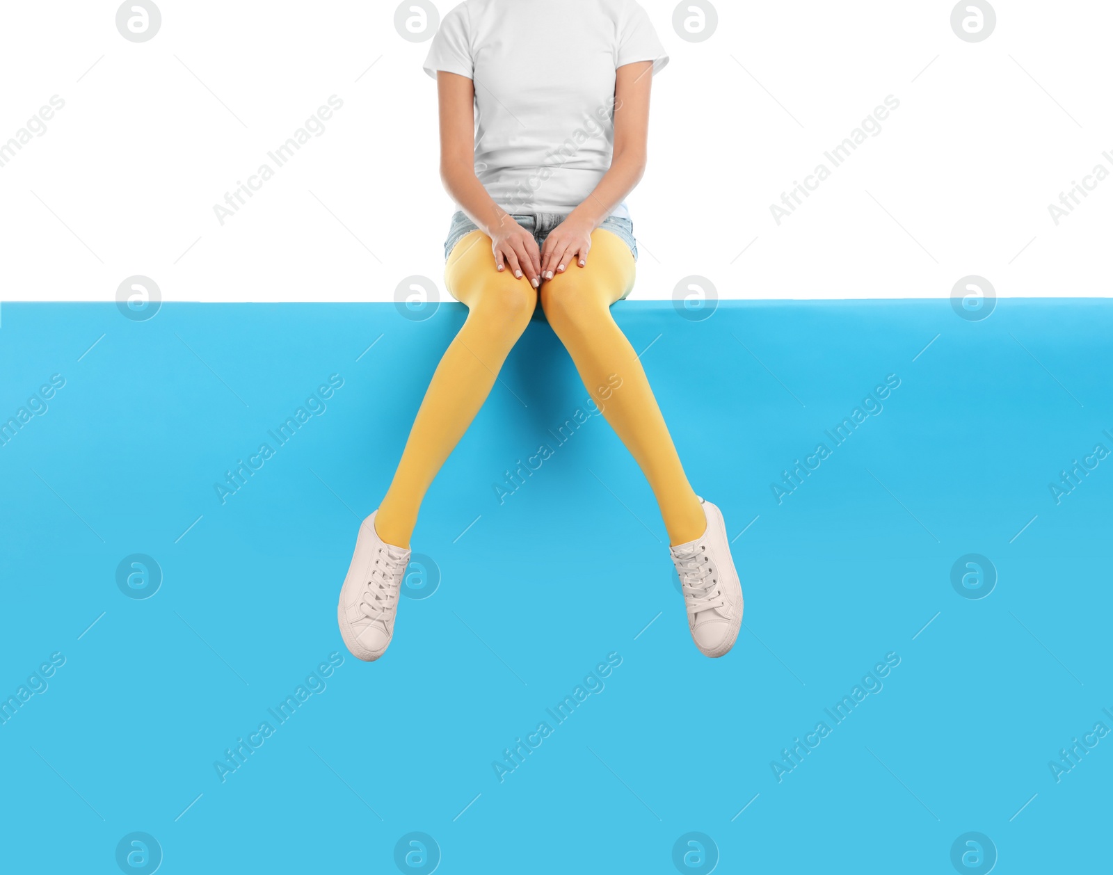 Photo of Woman wearing yellow tights and stylish shoes sitting on color background, closeup