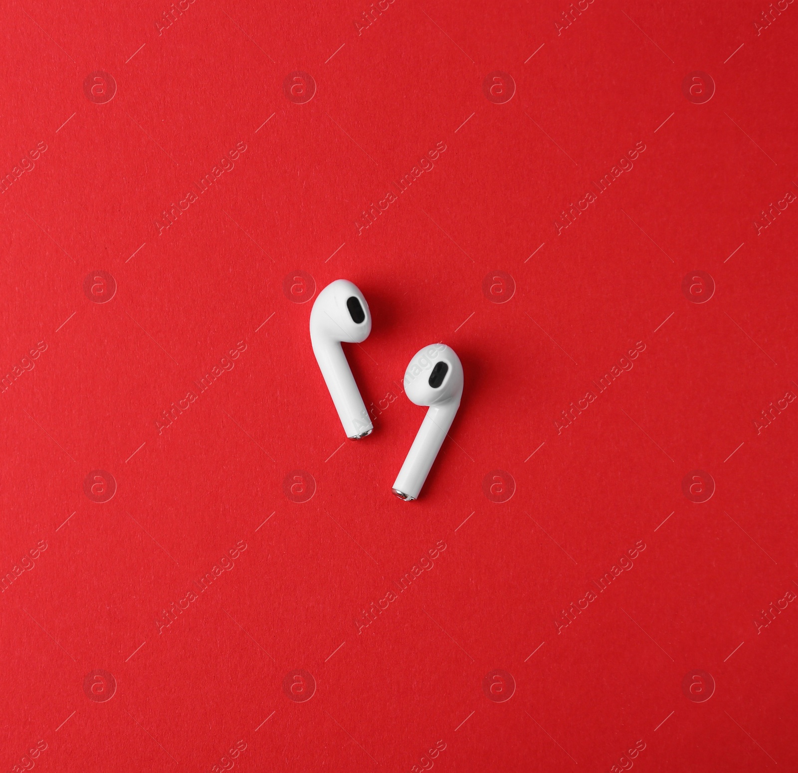 Photo of Modern wireless earphones on red background, flat lay. Space for text