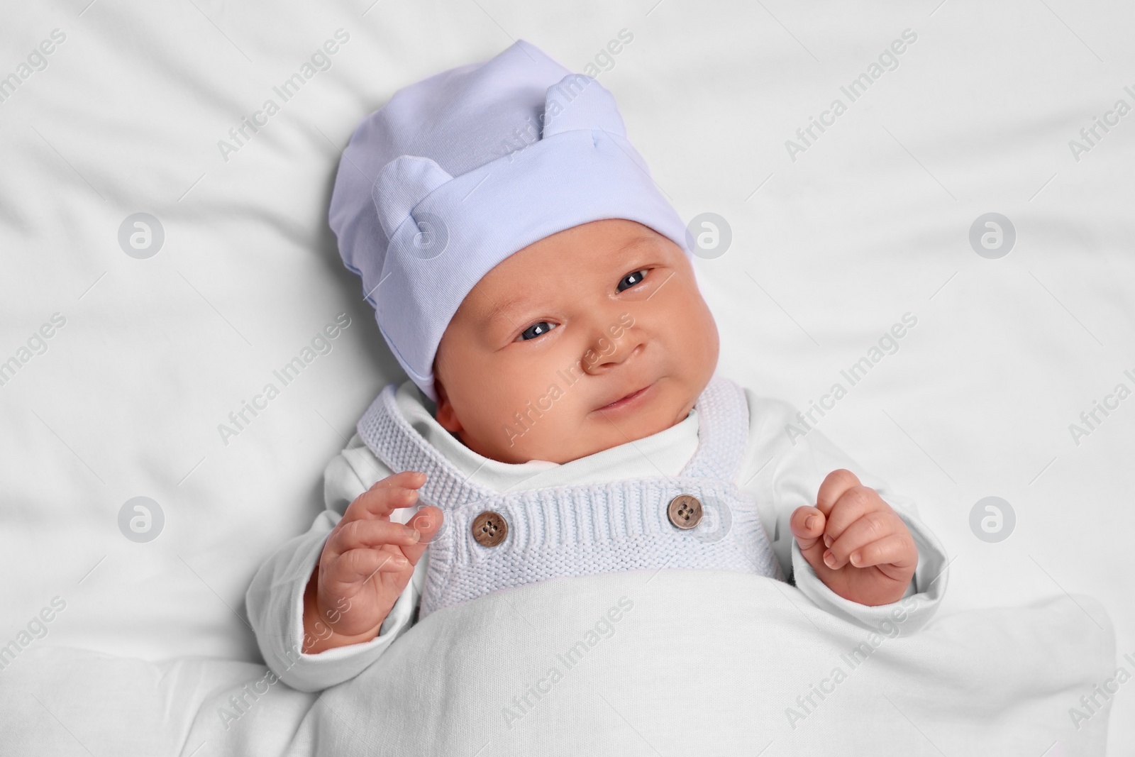 Photo of Cute newborn baby lying on white blanket, top view