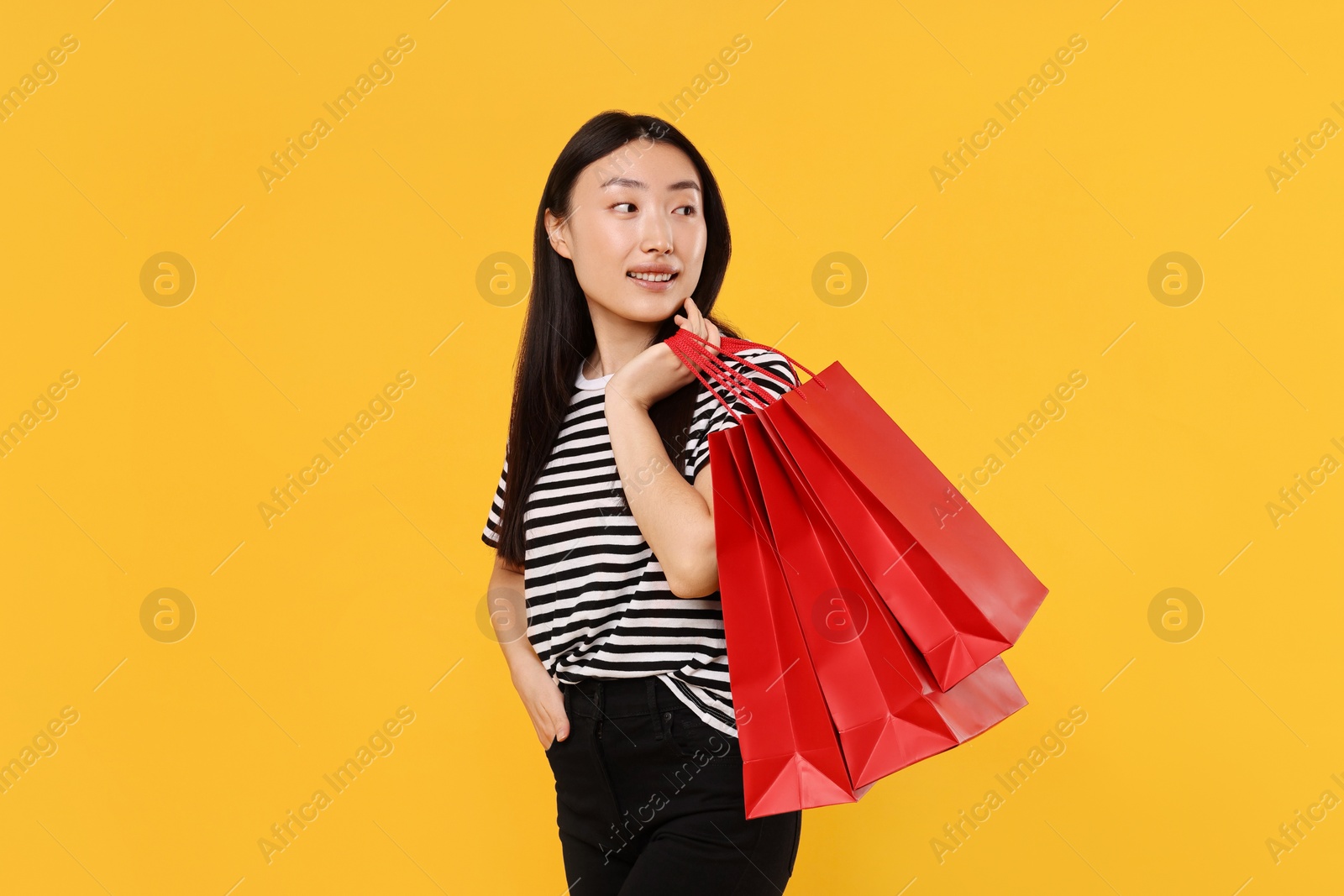 Photo of Smiling woman with shopping bags on yellow background