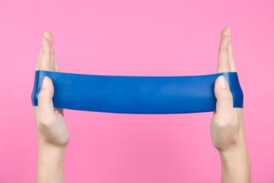 Photo of Woman with fitness elastic band on pink background, closeup